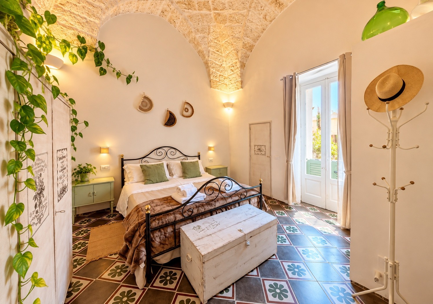 Interno con letto in ferro e pavimento decorato